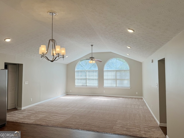 interior space with a textured ceiling, carpet flooring, ceiling fan with notable chandelier, and vaulted ceiling