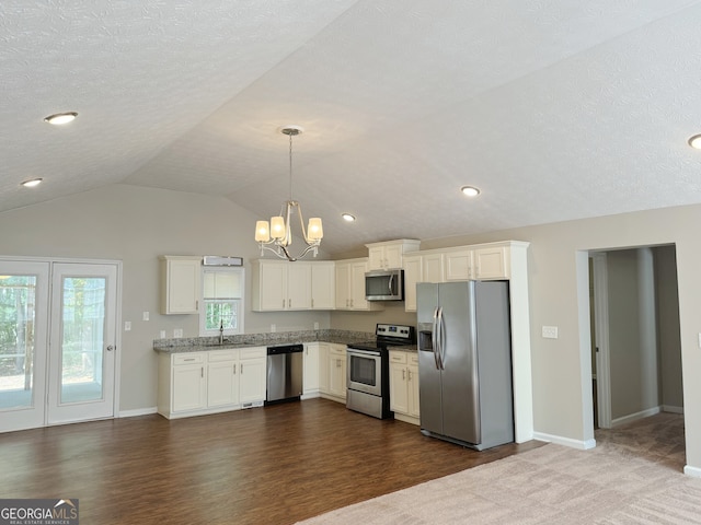 kitchen with appliances with stainless steel finishes, dark hardwood / wood-style flooring, white cabinets, hanging light fixtures, and lofted ceiling