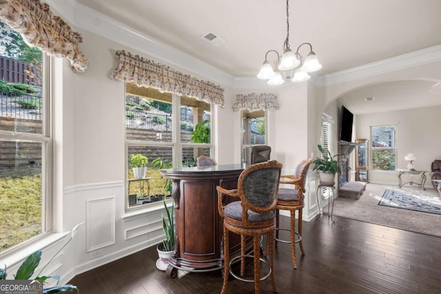 bar featuring crown molding, dark hardwood / wood-style flooring, a chandelier, and decorative light fixtures