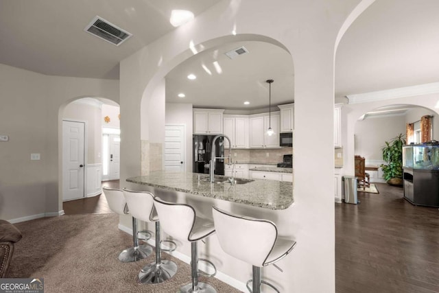 kitchen with sink, light stone counters, kitchen peninsula, pendant lighting, and white cabinets