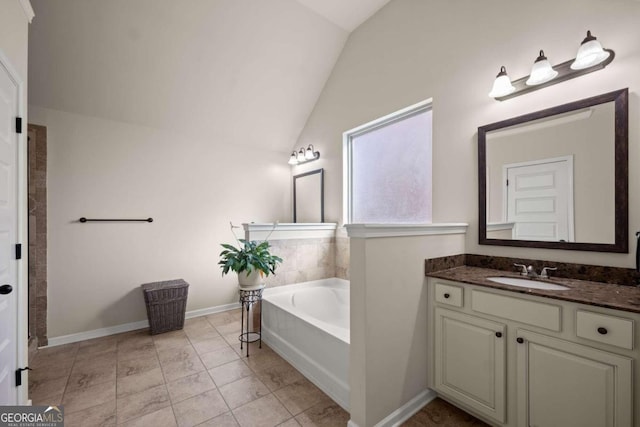 bathroom featuring a bathing tub, vanity, lofted ceiling, and tile patterned floors