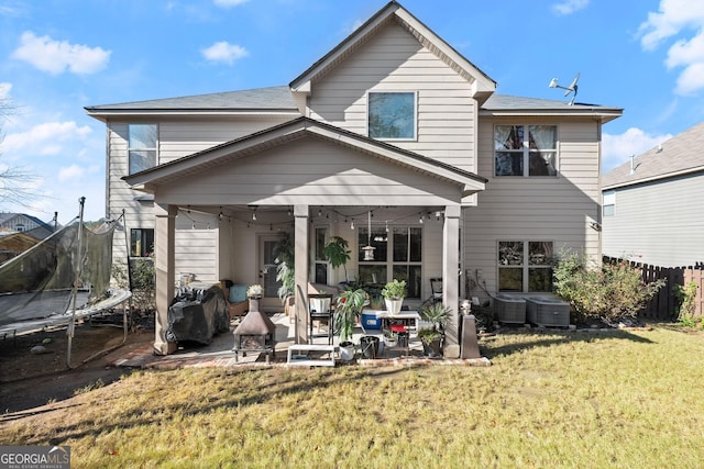 back of house featuring a yard, cooling unit, a patio, and a trampoline