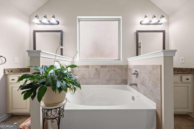 bathroom featuring a bath, vanity, and vaulted ceiling