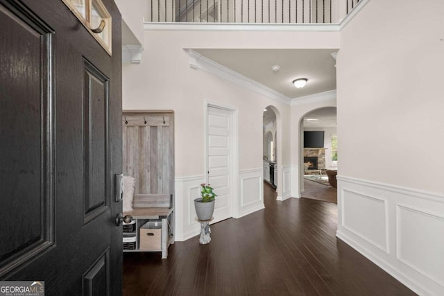 entryway featuring a stone fireplace, dark hardwood / wood-style flooring, and ornamental molding