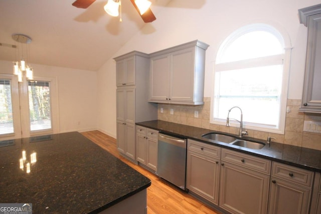 kitchen featuring dishwasher, sink, light hardwood / wood-style flooring, dark stone countertops, and vaulted ceiling