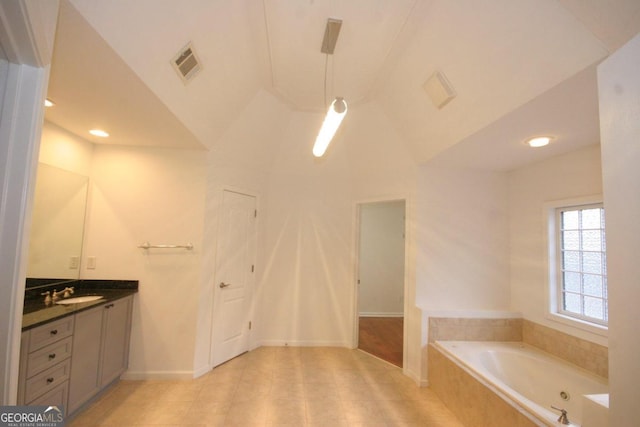 bathroom featuring vanity, tiled bath, and vaulted ceiling