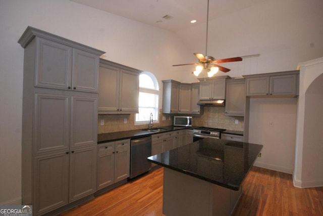 kitchen with lofted ceiling, sink, a kitchen island, wood-type flooring, and stainless steel appliances