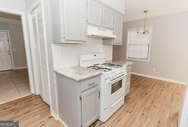 kitchen featuring tasteful backsplash, gas range gas stove, decorative light fixtures, light hardwood / wood-style flooring, and a chandelier