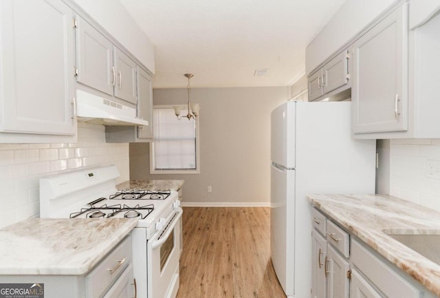 kitchen featuring hanging light fixtures, an inviting chandelier, backsplash, light hardwood / wood-style floors, and white appliances