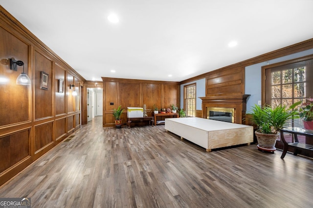 bedroom featuring hardwood / wood-style floors, wood walls, and crown molding