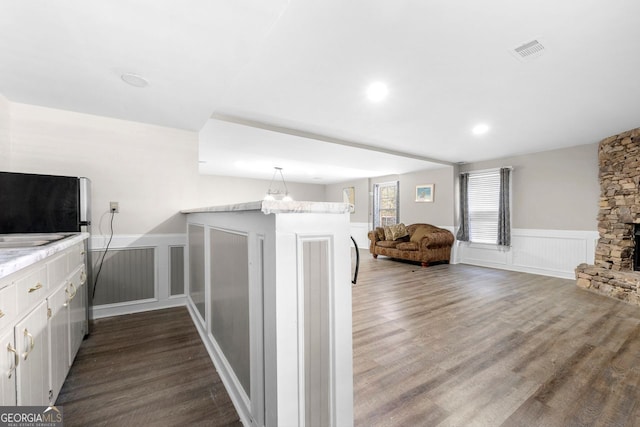 interior space with kitchen peninsula, hardwood / wood-style flooring, white cabinetry, and a fireplace