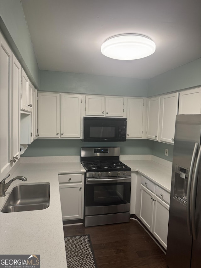 kitchen featuring appliances with stainless steel finishes, white cabinetry, dark wood-type flooring, and sink