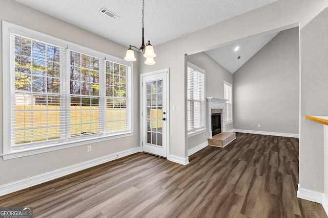 unfurnished dining area featuring a notable chandelier, a healthy amount of sunlight, lofted ceiling, and wood-type flooring