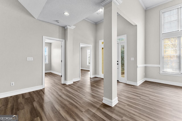 entrance foyer with dark hardwood / wood-style floors, ornamental molding, and decorative columns