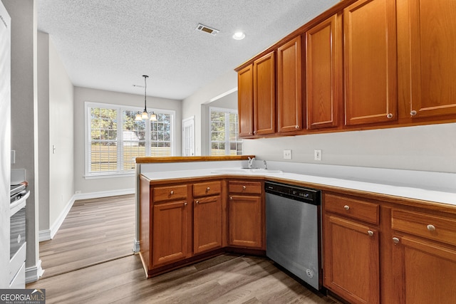 kitchen featuring sink, hanging light fixtures, stainless steel dishwasher, hardwood / wood-style floors, and a chandelier