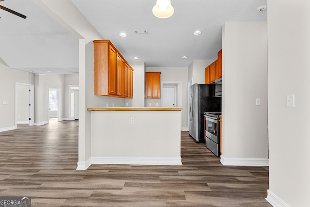 kitchen with appliances with stainless steel finishes, a textured ceiling, ceiling fan, and dark wood-type flooring