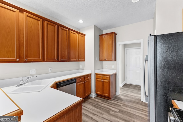 kitchen featuring sink, light wood-type flooring, a textured ceiling, and appliances with stainless steel finishes