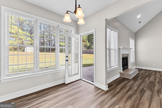 doorway featuring a tile fireplace, hardwood / wood-style floors, plenty of natural light, and lofted ceiling