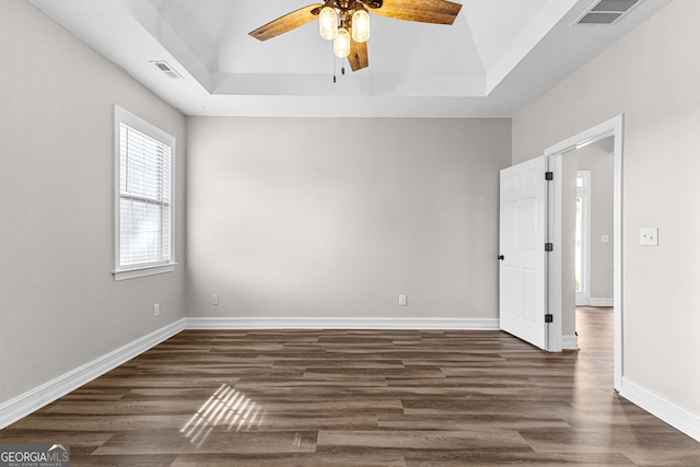 spare room featuring a tray ceiling, ceiling fan, and dark hardwood / wood-style floors