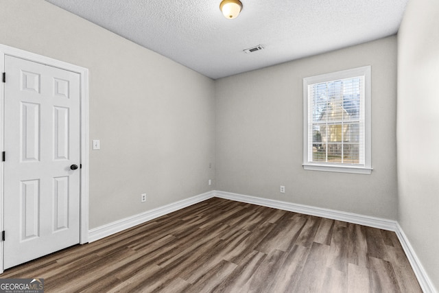 unfurnished room with a textured ceiling and dark hardwood / wood-style floors