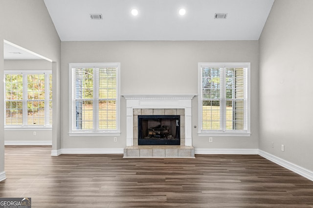 unfurnished living room with a wealth of natural light, dark wood-type flooring, and vaulted ceiling