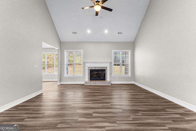 unfurnished living room featuring dark hardwood / wood-style floors, ceiling fan, a tile fireplace, and high vaulted ceiling