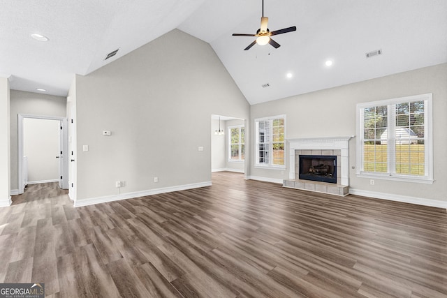 unfurnished living room with a fireplace, high vaulted ceiling, plenty of natural light, and dark wood-type flooring