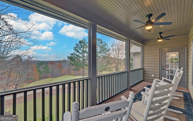 sunroom / solarium with a mountain view, ceiling fan, and wooden ceiling