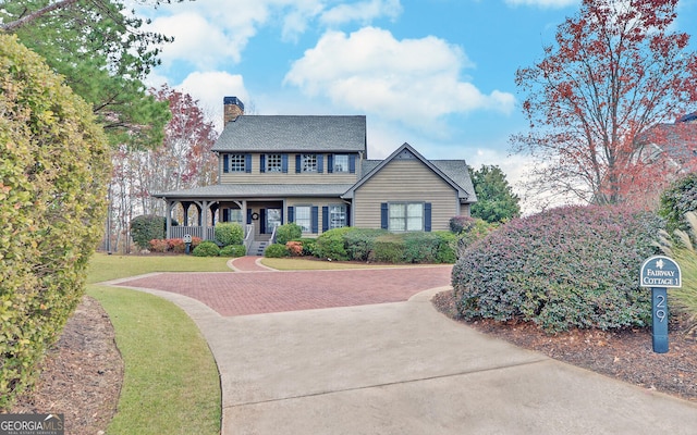 colonial-style house featuring a front lawn and covered porch