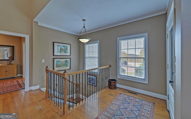 hall with light hardwood / wood-style flooring and crown molding