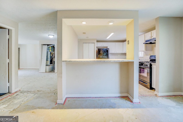 5267 Tasman Trl, Lithonia, GA 30038 - kitchen with black gas stove, freestanding refrigerator, under cabinet range hood, white cabinets, and light countertops