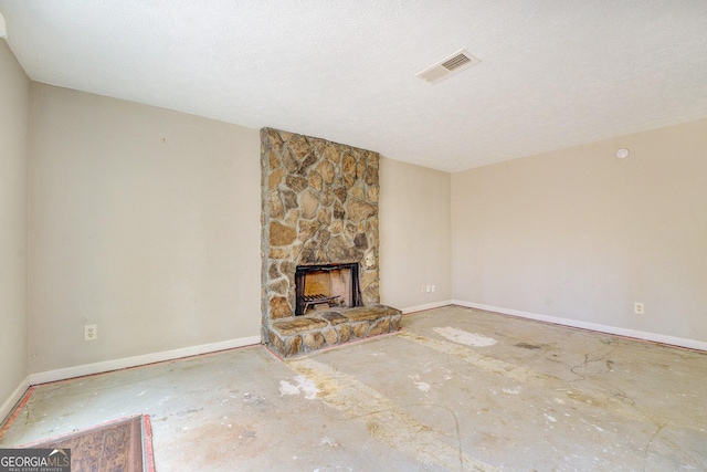 unfurnished living room featuring a textured ceiling and a stone fireplace