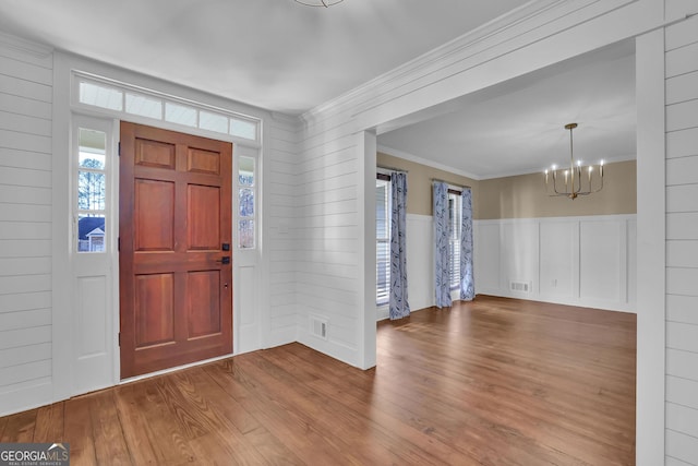 entryway featuring light hardwood / wood-style floors, crown molding, and a notable chandelier