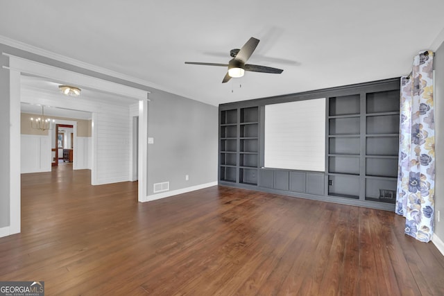 unfurnished living room with built in shelves, dark hardwood / wood-style flooring, ornamental molding, and ceiling fan with notable chandelier