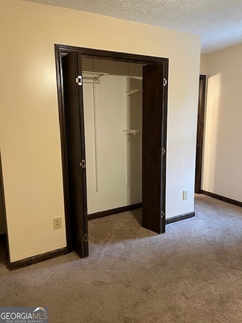 unfurnished bedroom with light carpet, a textured ceiling, and a closet