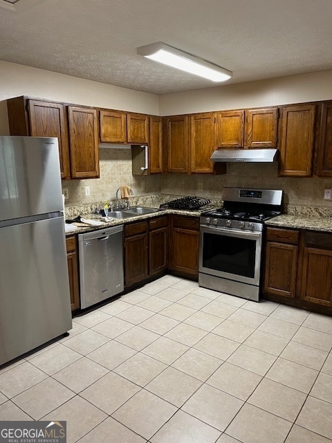 kitchen with backsplash, light tile patterned floors, sink, and appliances with stainless steel finishes