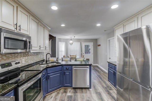 kitchen featuring light hardwood / wood-style flooring, appliances with stainless steel finishes, sink, dark stone counters, and blue cabinets