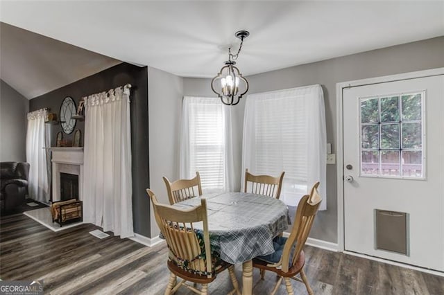 dining room featuring an inviting chandelier, dark hardwood / wood-style floors, and vaulted ceiling