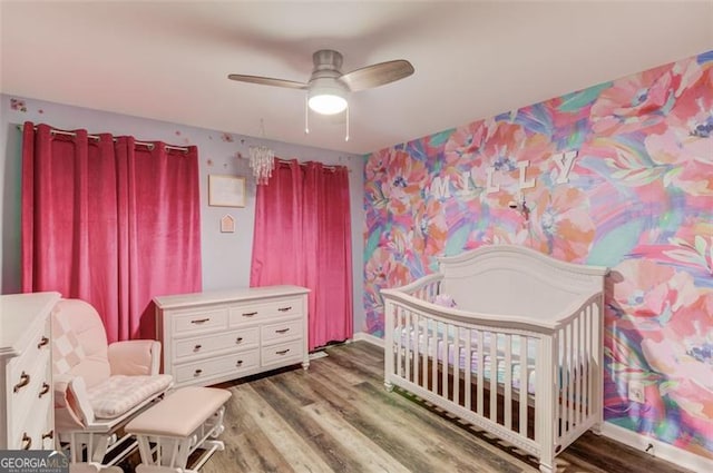 bedroom with ceiling fan, hardwood / wood-style floors, and a crib