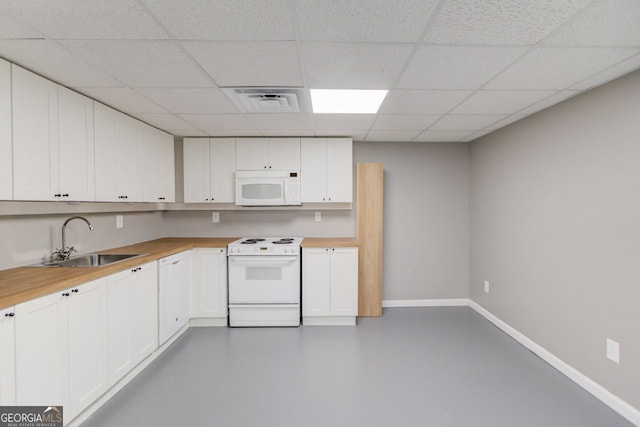 kitchen with concrete floors, white appliances, butcher block counters, white cabinetry, and sink