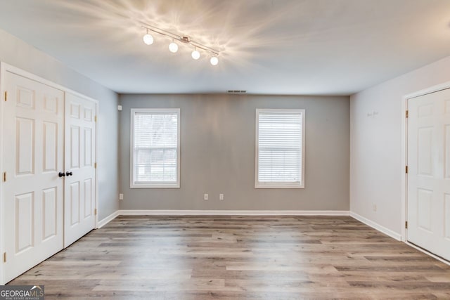 unfurnished bedroom with rail lighting and light hardwood / wood-style flooring