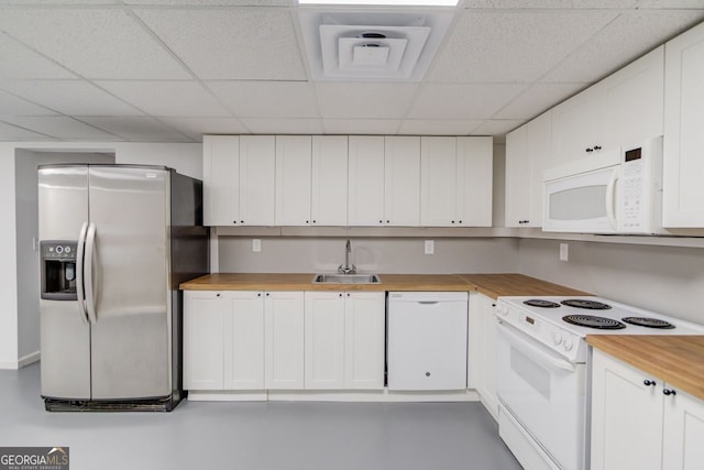 kitchen with sink, white cabinetry, butcher block countertops, white appliances, and a drop ceiling