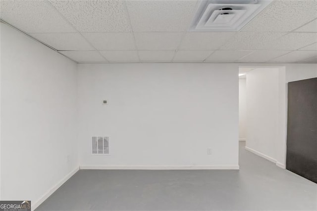 unfurnished room with a paneled ceiling and concrete flooring