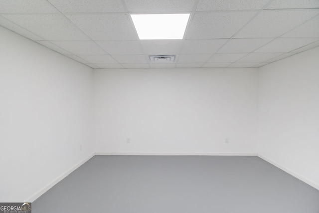 empty room with a paneled ceiling and concrete flooring