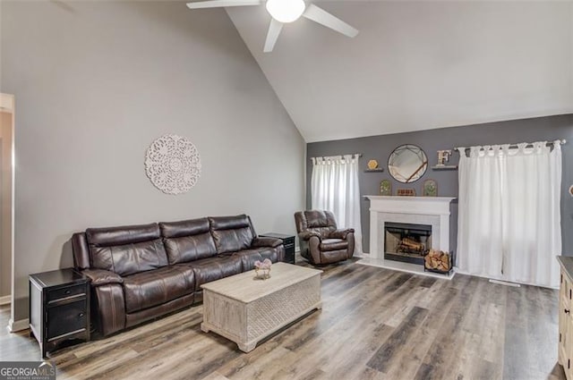 living room with hardwood / wood-style flooring, ceiling fan, and vaulted ceiling