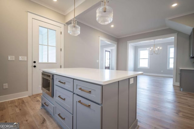 kitchen with stainless steel appliances, pendant lighting, a kitchen island, and light hardwood / wood-style floors