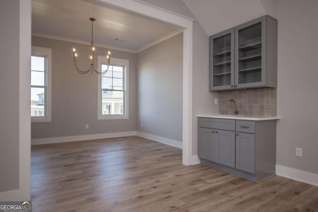 unfurnished dining area featuring an inviting chandelier, light hardwood / wood-style flooring, and ornamental molding