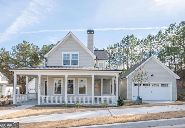 farmhouse-style home with a porch, a garage, and an outdoor structure