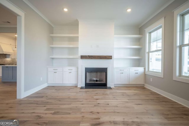 unfurnished living room featuring built in features, ornamental molding, and light hardwood / wood-style flooring