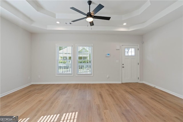 entryway with light wood-type flooring, a tray ceiling, and ceiling fan